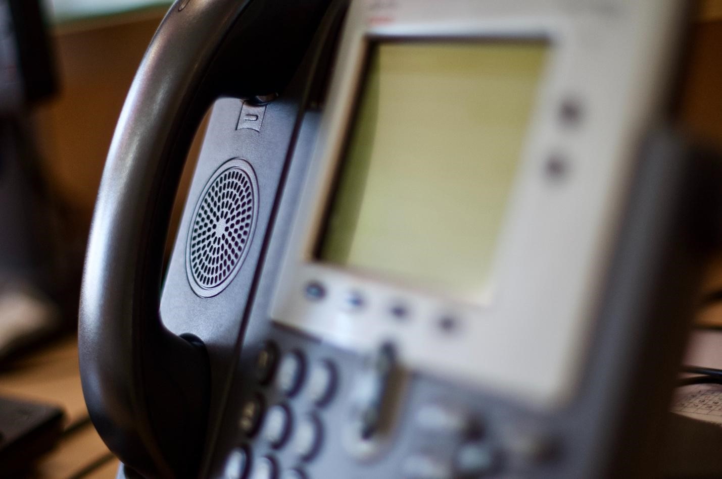 A closeup of an office phone on a desk.